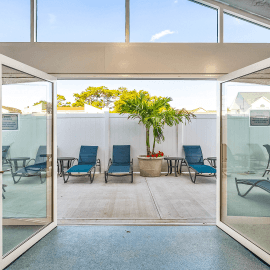 Glass doors opening to the outdoor sundeck with blue loungechairs